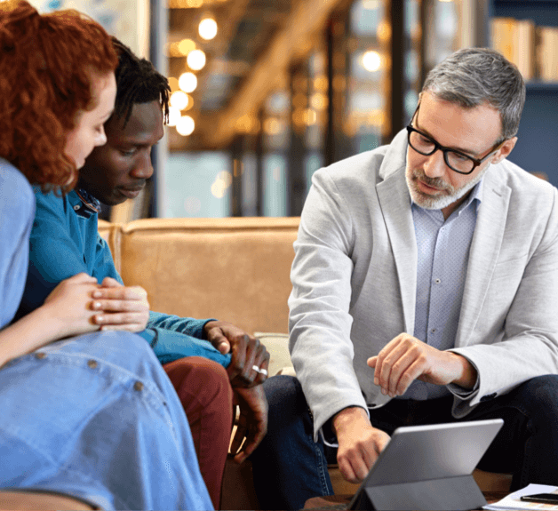 Younger male and female learning from an older male colleague