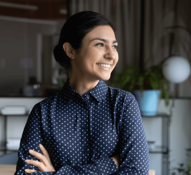Smiling woman in office setting, standing with arms crossed
