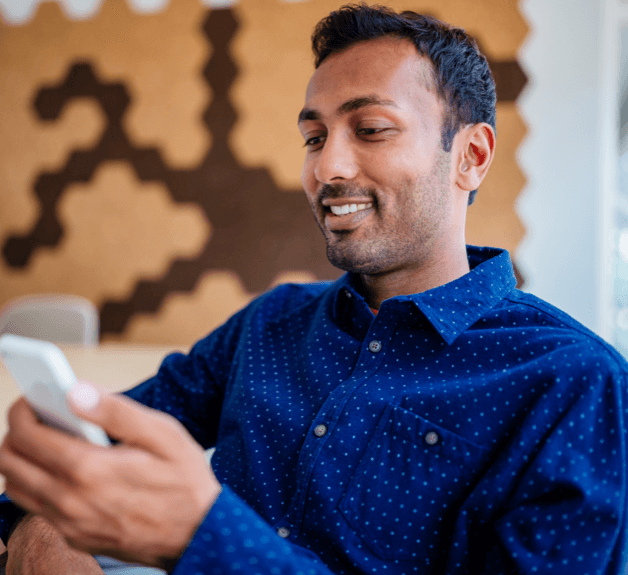 Male employee, smiling and sitting back looking at his phone